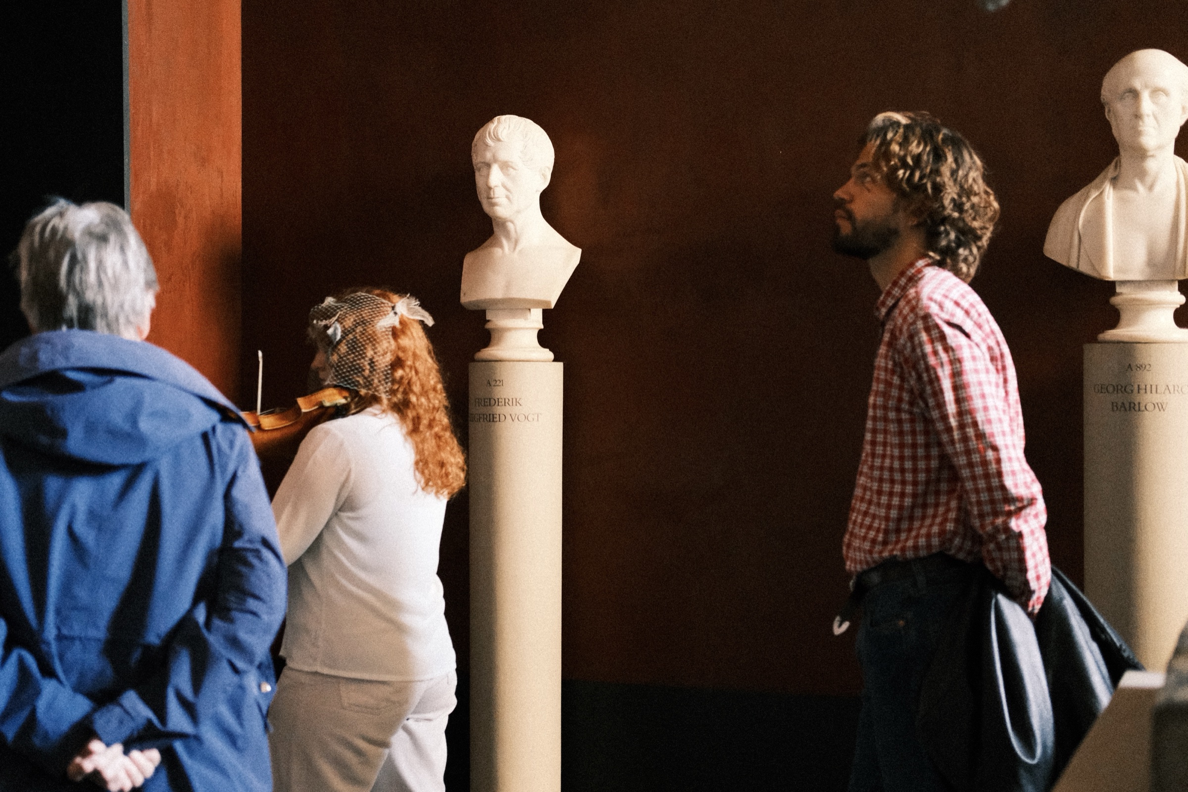 Guests listening to the violinist between two busts
