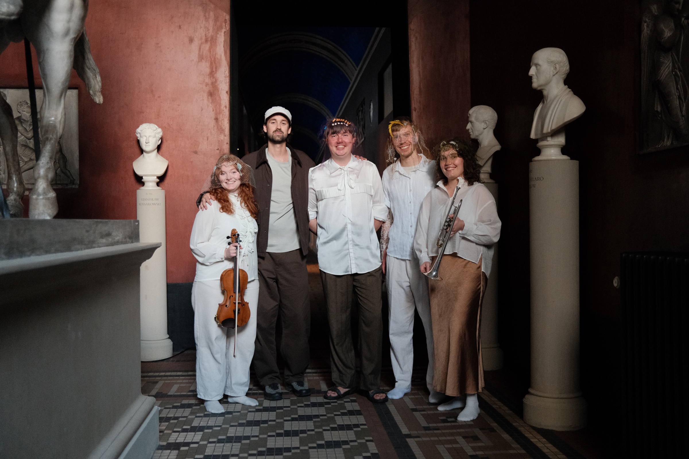 The five people behind SPEKTRUM, smiling in a corridor at Thorvaldsens Museum