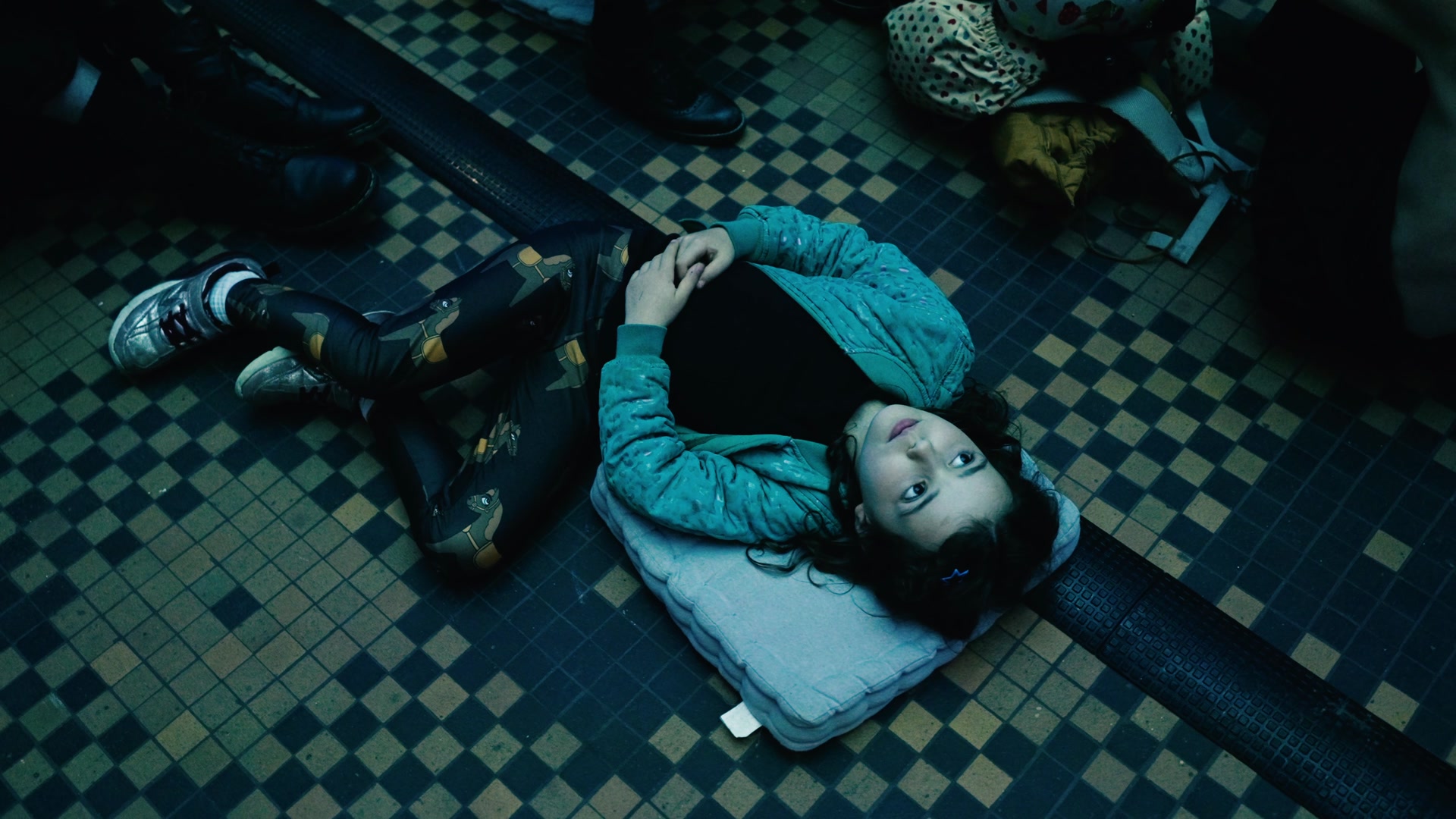 A child lying on a cushion on the tiled floor